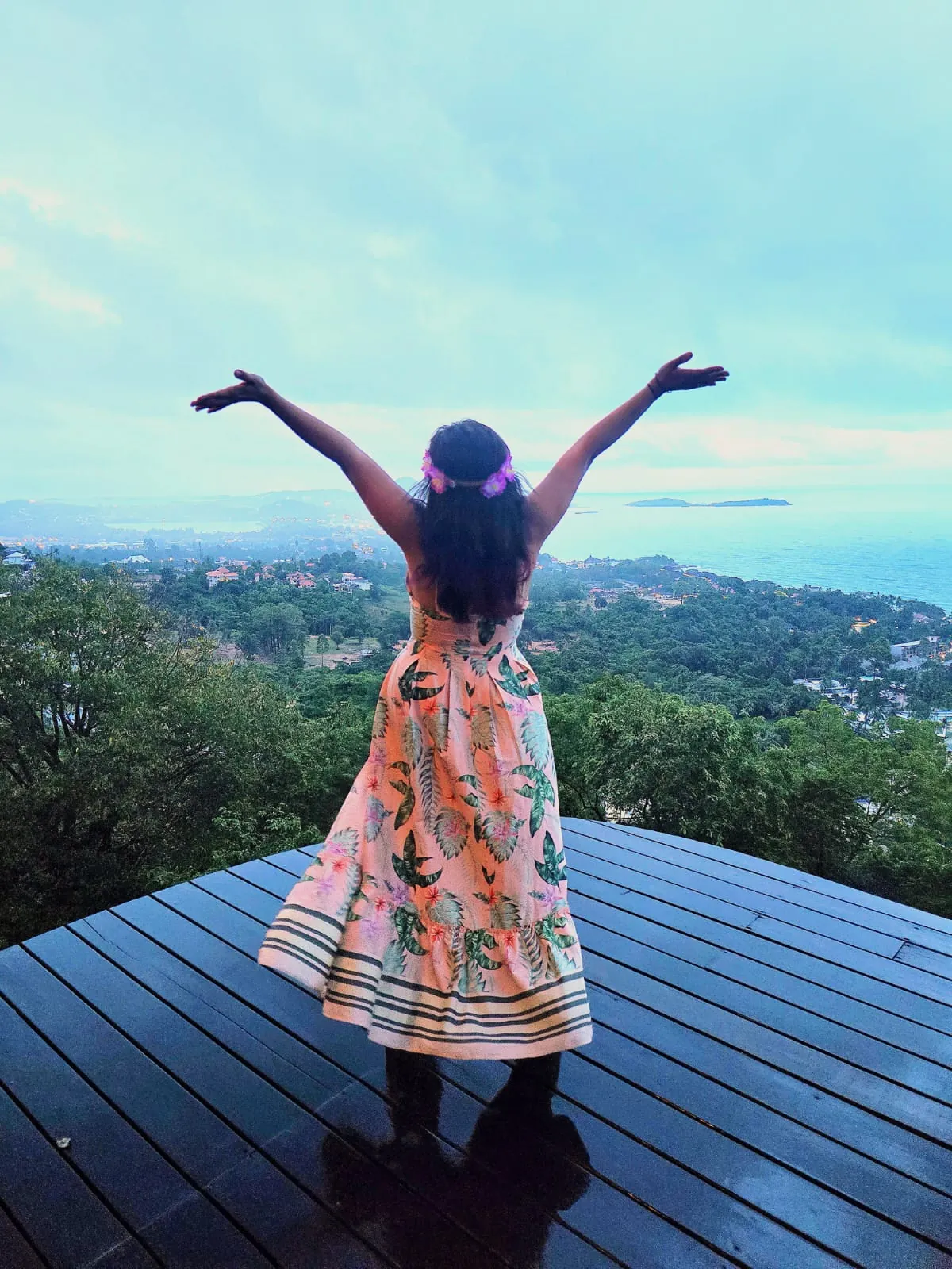 Mona El-Gazzar with arms outstretched overlooking the sea and green landscape