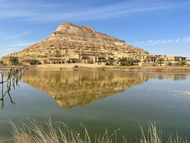 A mountain reflected in a still lake in Siwa